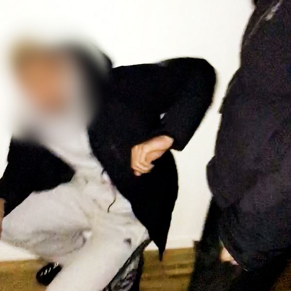 Ung man hotas ner på knä av en annan man med pistol