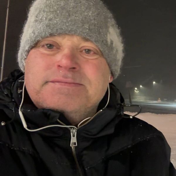 En man i grå mössa står ute i snöoväder