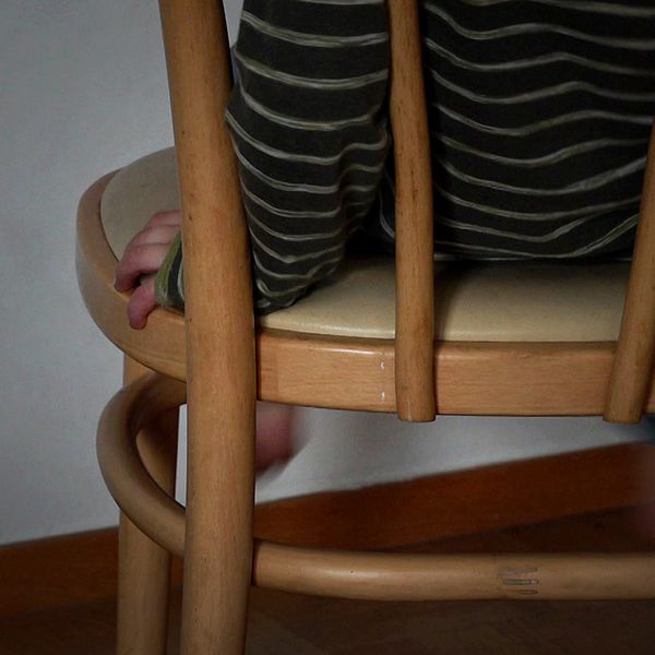 Lina Axelsson Kihlblom tittar in i kameran, och ett barn som sitter på en stol, fötterna syns