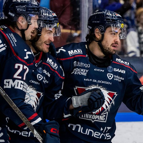 På vänster sida av bilden syns tre ishockeyspelare från Linköping HC i matchställ, samlade som om de firar eller diskuterar något under en match. På höger sida av bilden ses en fjärde spelare från samma lag iförd nummer 18 utföra en aktion på isen, medan en motståndare i blå och gul dräkt syns delvis nere på isen.