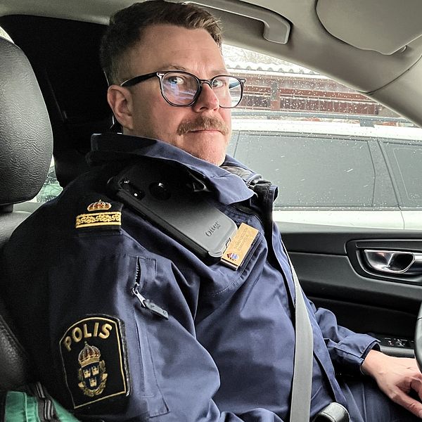 En man med glasögon och mustasch, polisen Thomas Nordström, sitter i polisuniform i en polisbil i Avesta.