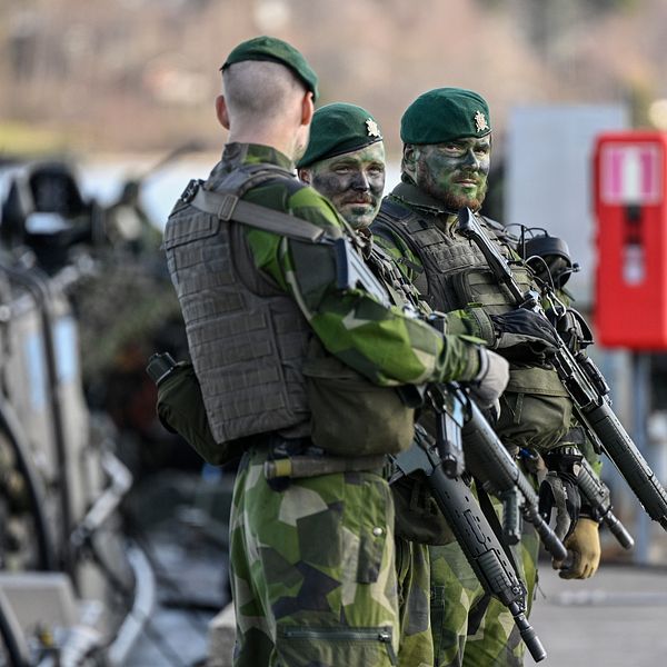 Militärer med skyddsväst och vapen till vänster. SVT:s reporter Serafia Olausson tittar in i kameran till höger