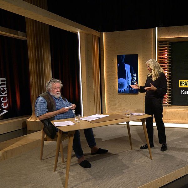 Leif GW Persson sitter och bläddrar i papper i studion, medan Camilla Kvartoft står upp och diskuterar ämnet för programmet Veckan. Skärmen bakom dem visar en bild med texten ”Brattås – Kan dubbelmordet lösas med DNA?”