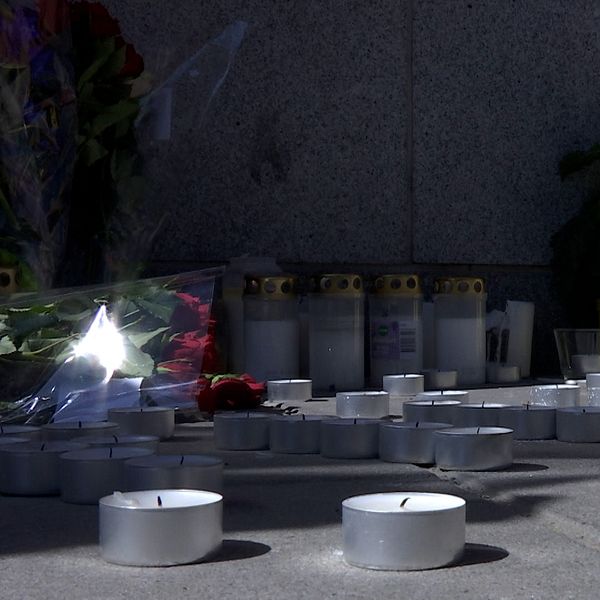 Blommor och ljus ligger vid en minnesstundsplats för ett brottsoffer.