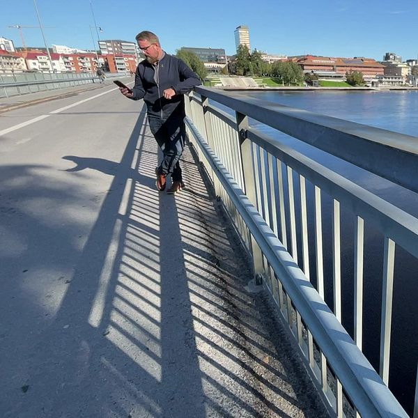 Per Boström (KD) står på en bro i centrala Skellefteå och tittar ner i sin mobiltelefon