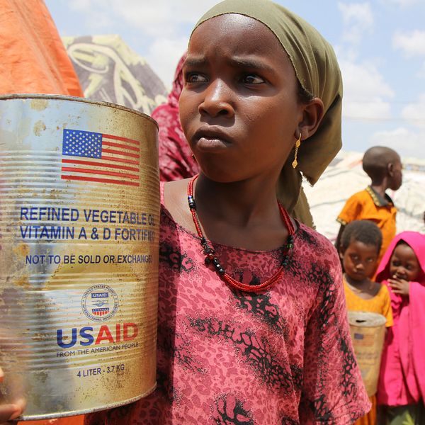 Barn i flyktingläger, ett barn håller en burk med biståndsmat från USAID.