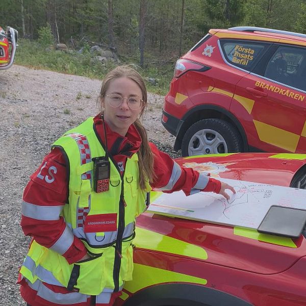 kvinnlig räddningsledare som pekar på en karta över brandområdet, helikopter som vattenbombar