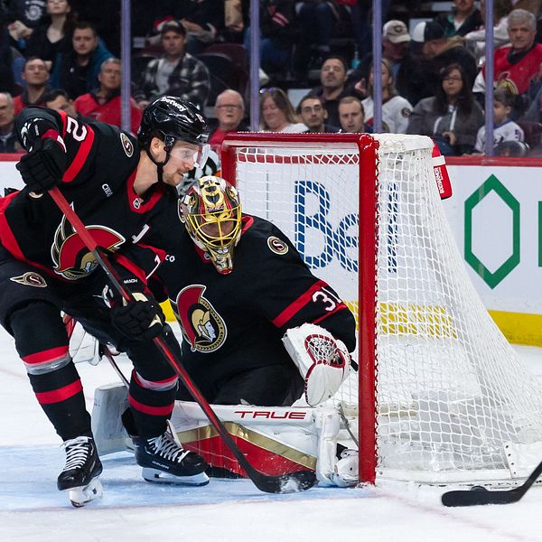 Hockeyspelare i action nära målvakt. Panthers-spelare hanterar pucken.