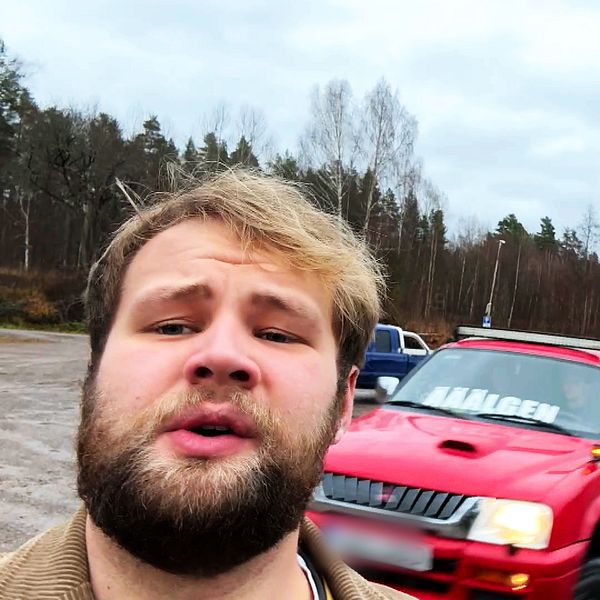 En man står framför tre a-traktorer som kör iväg från en grusig parkeringsplats.