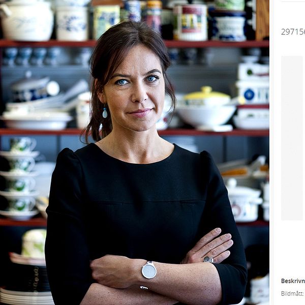Stockholms auktionverks vd Li Pamp står med armarna i kors. Bredvid henne syns en av tavlorna, ett screentryck föreställande Elvis i rött och vitt.
