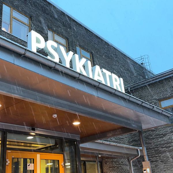 Till vänster syns fasaden och entrén till psykiatrin vid centralsjukhuset i Karlstad. Till höger syns en person med skägg iförd en kostym och en mikrofon med SVT:s logotyp synlig.