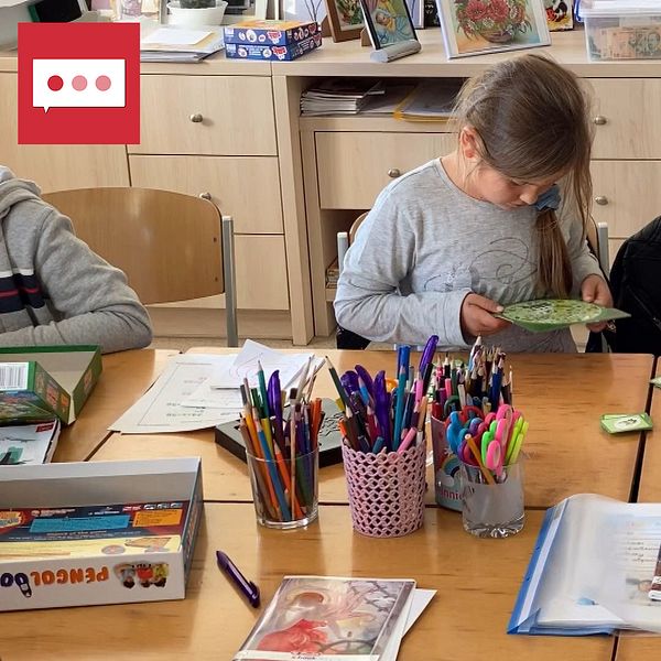 klassrum på flyktingcenter i rumänska Suceava. Två flickor pysslar och den ena pekar på någonting. På bordet står burkar med pennor och olika sorters skolmaterial