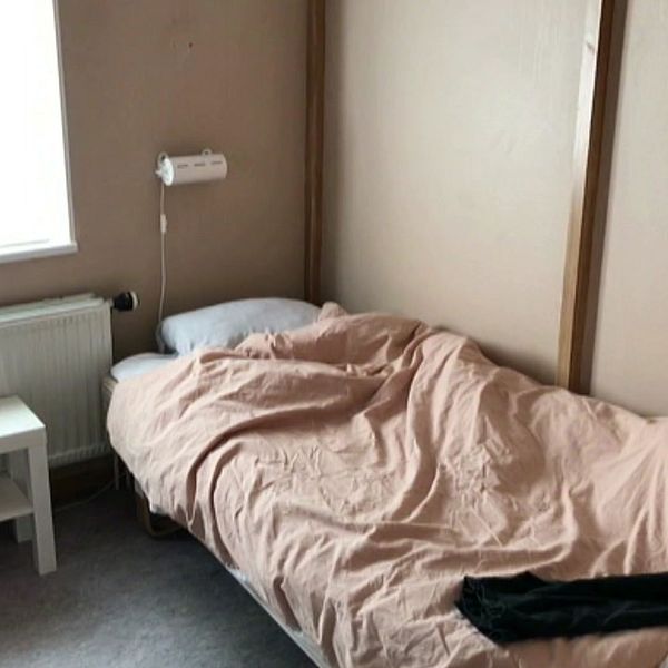 En tom säng och en bild på en kvinna.