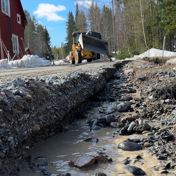 Delad bild. En grusväg som delvis spolats bort med en traktor i bakgrunden och en man i keps och varselväst.