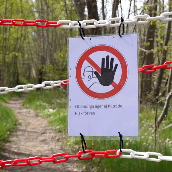 Förbudsskylt framför naturstig, kvinna med glasögon.