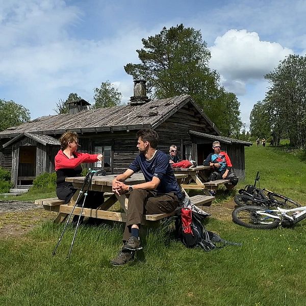 Turister sitter på en bänk utanför finngården Ritamäki.