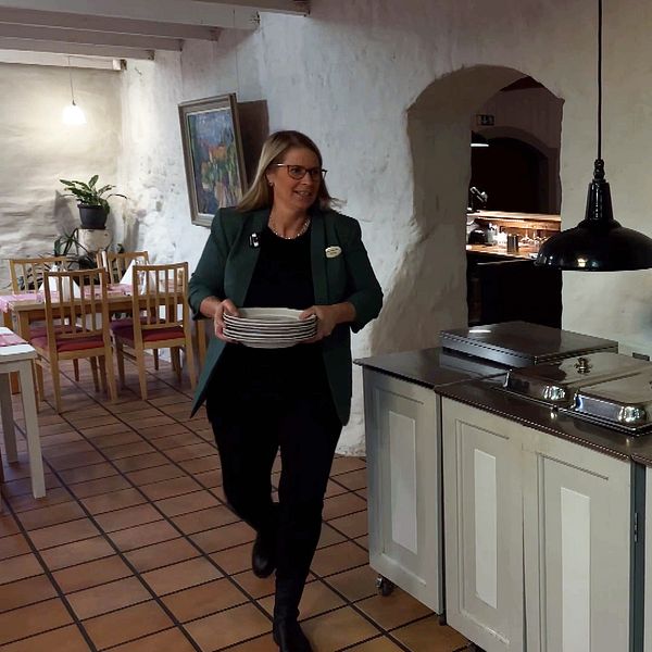Anna Sahlström Mirkovic bär tallrikar i restaurangen på Sahlströmsgården.