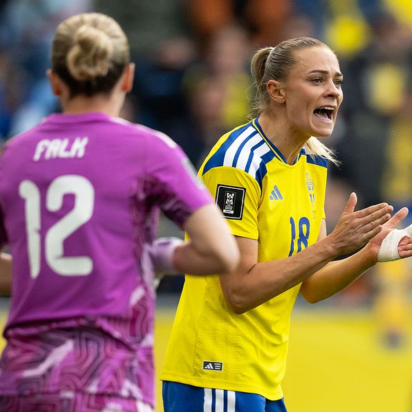 Svenska fotbollsspelare i gult och motståndare i lila under matchen