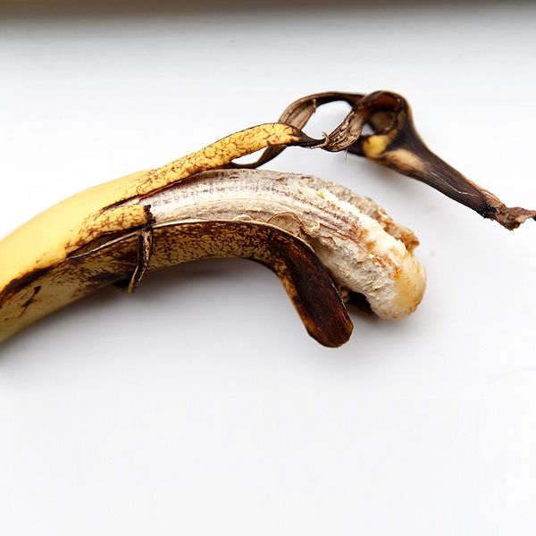 Trött gulbrun banan och närbild på naken överkropp på man med hand som söker sig ned mot byxlinning