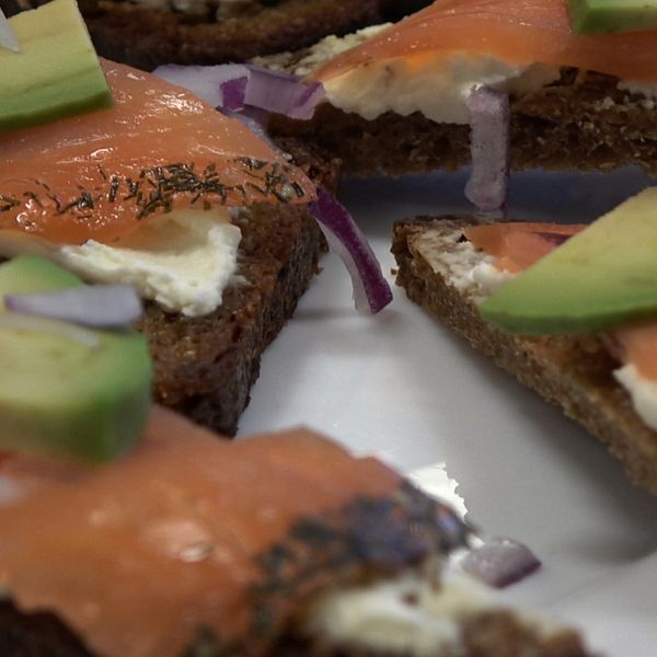 Snittar på rågbröd med lax och färskost till vänster. Linnéa Johansson, måltidsutvecklare, till höger.