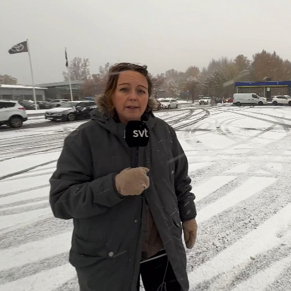 kvinna ute med mikrofon i handen framför bilar i kö