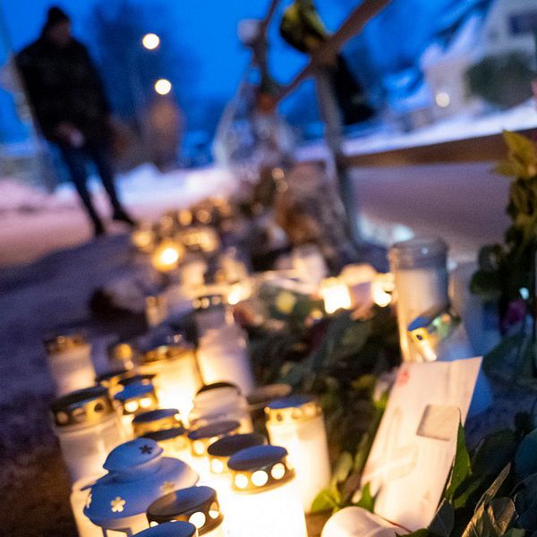 En delad bild som visar två scener. Den vänstra sidan visar en rad ljuslyktor och blommor som är placerade längs en väg i en lugn miljö som antyder ett minnesmärke. Den högra sidan visar SVT reportern Simon Melin som står och pratar i en offentlig miljö, med byggnader i bakgrunden och en grå himmel. Örkelljunga, mordet på Jakob Hall.