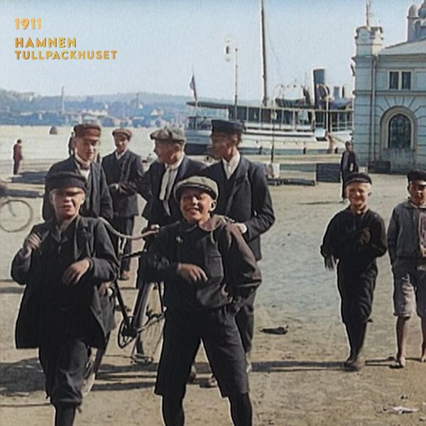 Pojkar och män vid Sundsvalls hamn och tullhus år 1911, med fartyg i bakgrunden.