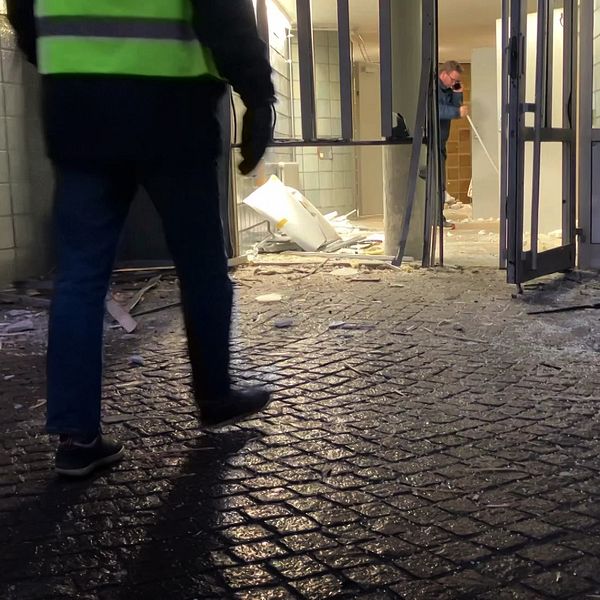 Personer jobbar med att städa och sopa vid en port i ett flerfamiljshus i Västra Frölunda i Göteborg där två explosioner inträffat