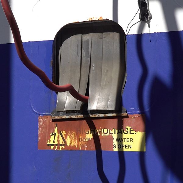 Delad bild. Vänster: laddstation på en båt. Höger: person i varselkläder bredvid laddstation.