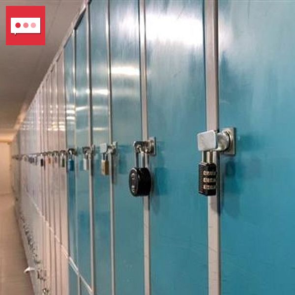 Rader av blåa skåp med hänglås på en skolkorridor, en person går längst bort i bakgrunden.