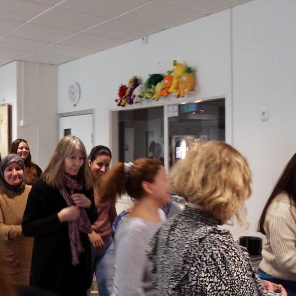 Bilden är en delad bild. Den första sektionen visar en grupp av människor som går i en korridor inomhus, möjligvis på en skola eller ett kontor, medan den andra sektionen visar en person i närbild, stående framför en hylla med färgglada leksaker eller figurer.