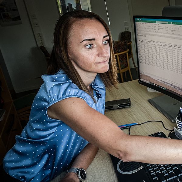 Zilha Fific är enhetschef på IFO Barn och familj vid Rättvik kommuns socialförvaltning. Hon har p åsig en blå kortärmad blus och pekar på en datorskärm med kalkylbladsark.