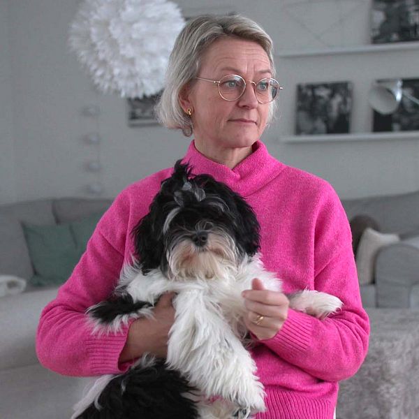 Pernilla Krokström med en hund i knäet. En skinkbit med vitt pulver på