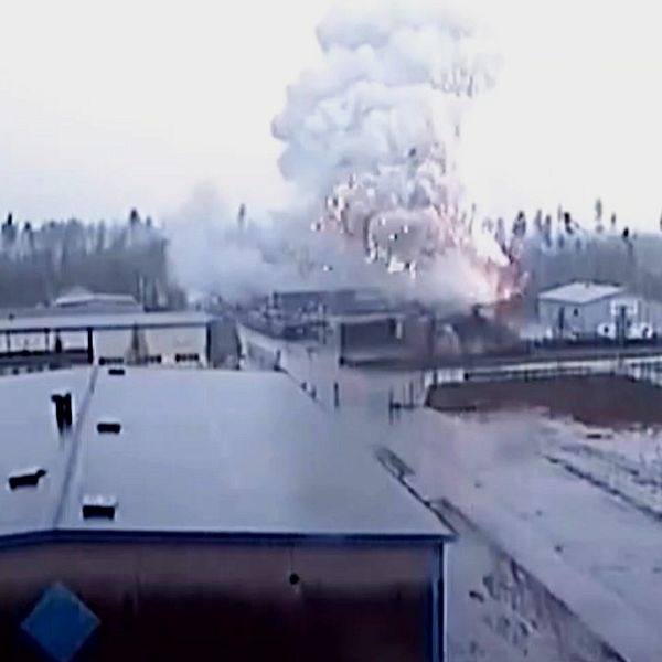 En delad bild som visar en explosion i en industriell miljö till vänster, där rök och eld stiger i luften, och en intervju med en person till höger i en inomhusmiljö, klädd i en rutmönstrad skjorta.