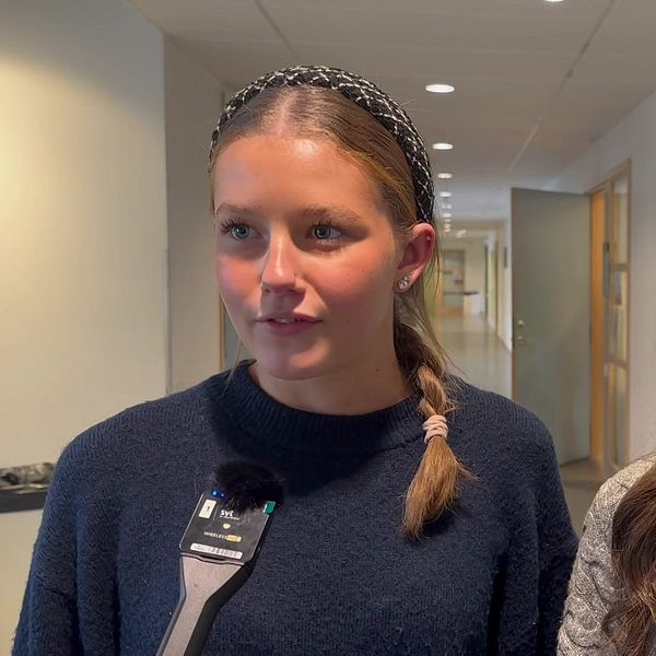 Till vänster står Filippa Swärd och till höger står Nellie Lindgren, de är elever på Sjöängsskolan i Askersund och går båda i årskurs två. De står i en korridor i skolan, men blåa skåp bakom sig.