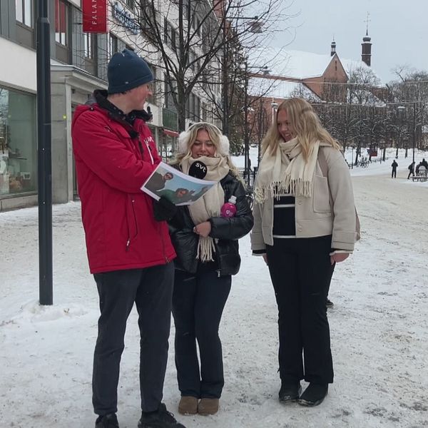 Reportern håller i en bild med Bolaget i ena handet, och står och intervjuar flera personer