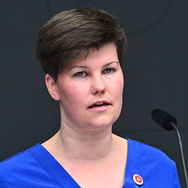 En kvinna med kort svart hår och en äldre man som kollar åt vänster