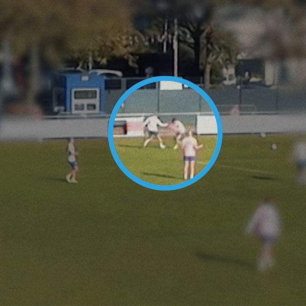 Fotbollsspelare på plan, till höger en tränare som kramar en spelare vid sidlinjen.
