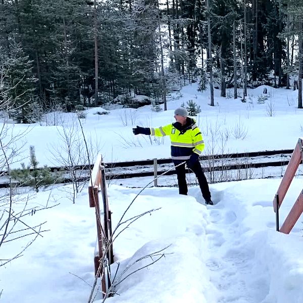 en man som står bredvid en järnväg och pekar.