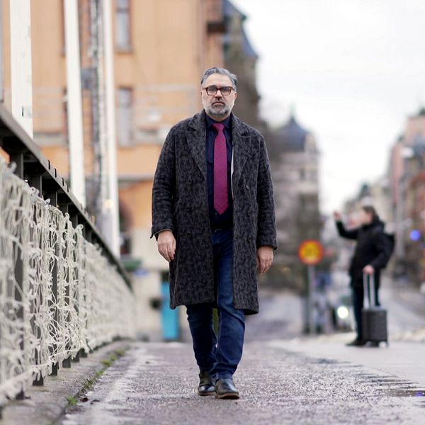 Eihab som intervjuas syns gåendes på en bro i centrala Norrköping. Han har flyttat dit efter att han flydde från Syrien. Till höger syns foten på ett av offren från syriske diktatorn Bashad al-Assads offer.
