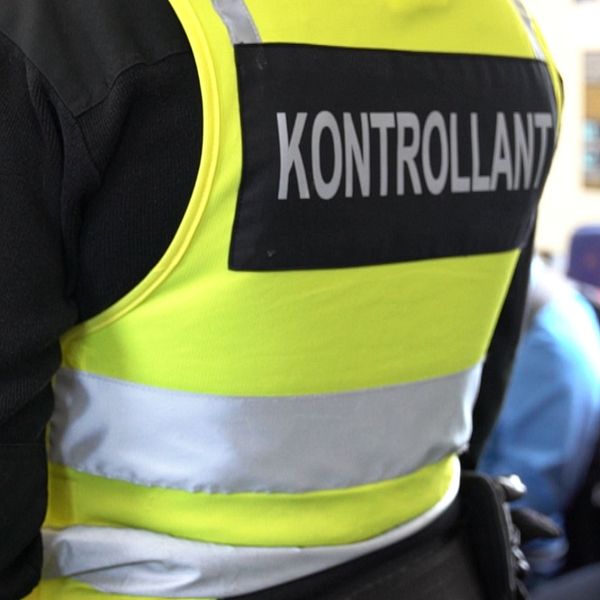 Kontrollant i reflexväst bredvid en man under biljettkontroll