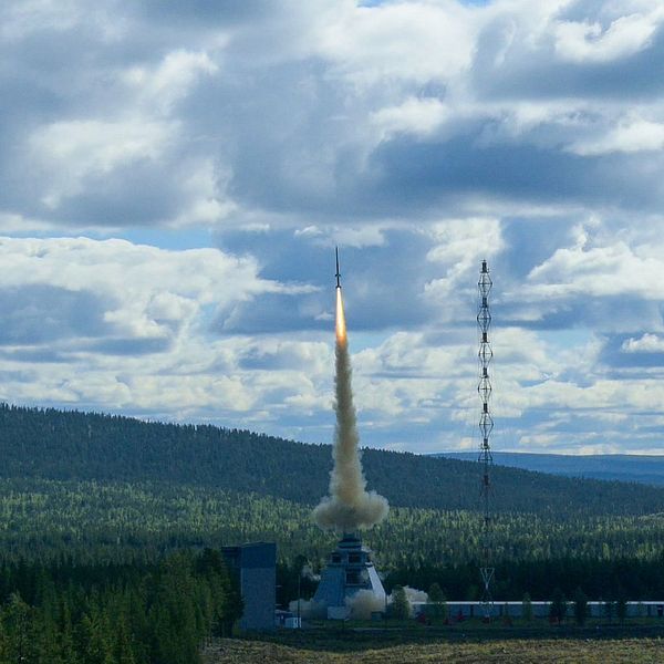 Raketen lyfter mot molnig himmel medan en porträttbild på influencern ”Mustiga Mauri” visas bredvid.