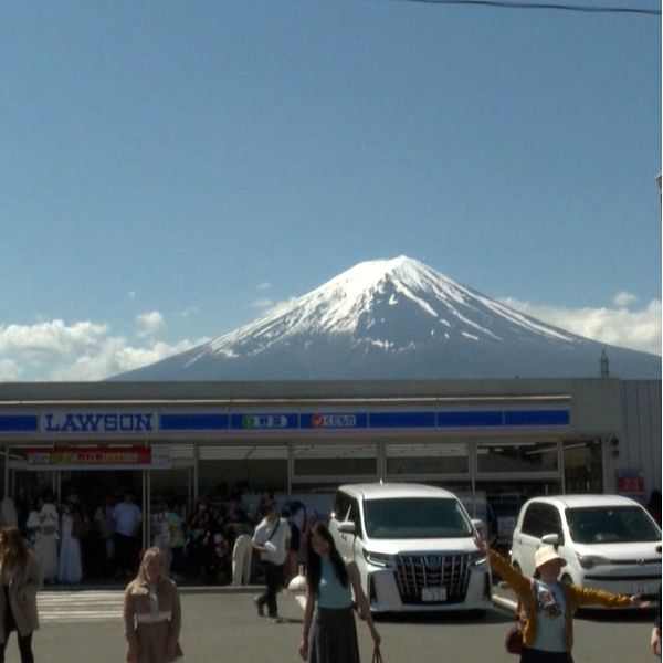 Turister står i en klunga och fotograferar berget Fuji.