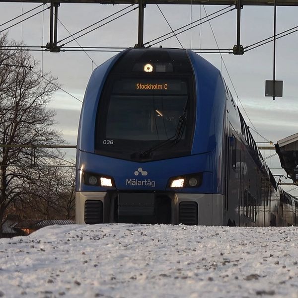 Ett blått tåg vid station, snö i förgrunden