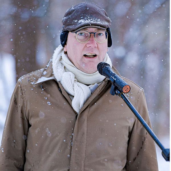En delad bild som visar två olika scener. Den vänstra sidan visar Gustav Hemming klädd i en brun jacka och vit scarf, omgiven av snöfall i en utomhusmiljö. Den högra sidan visar en annan person som bär en vit t-shirt och beige byxor, med en svart ryggsäck över axeln, gående inomhus i en modern miljö.