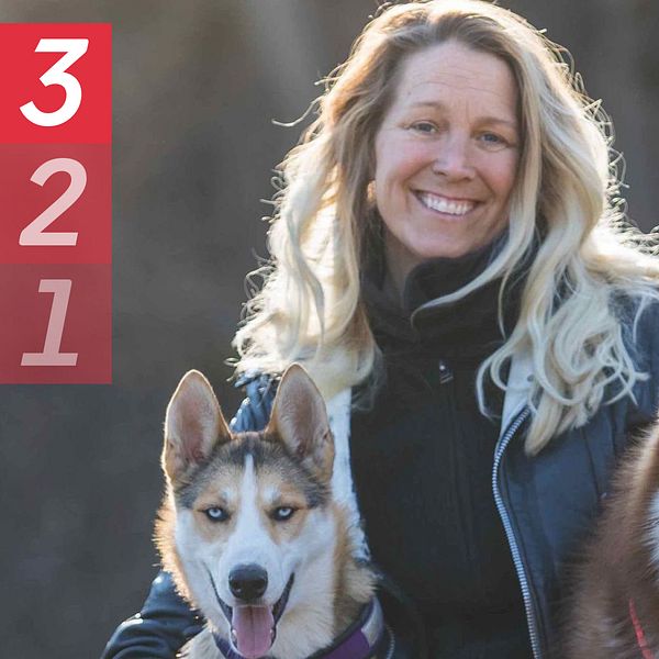 Hundpsykologen Tess Erngren utomhus som kramar om två hundar