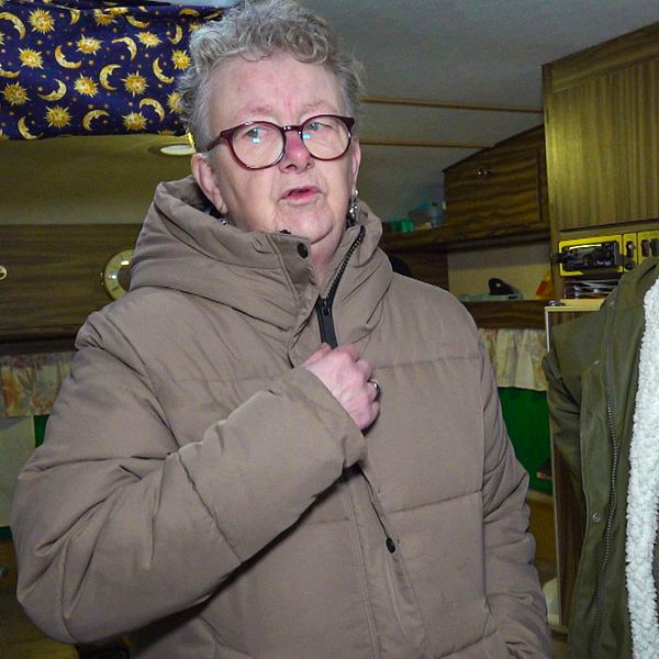 Två kvinnor med glasögon som står i en äldre husvagn. De har jackor på sig.