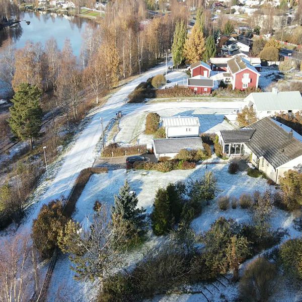 En gata med hus ovanifrån och en man med hatt och glasögon.