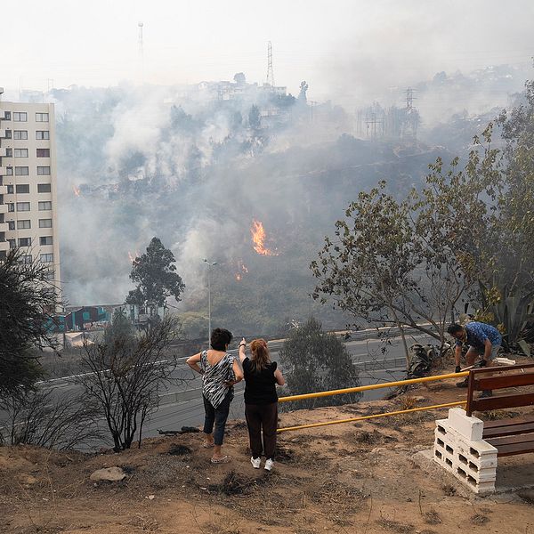 Människor tittar ut över en brand i Chile
