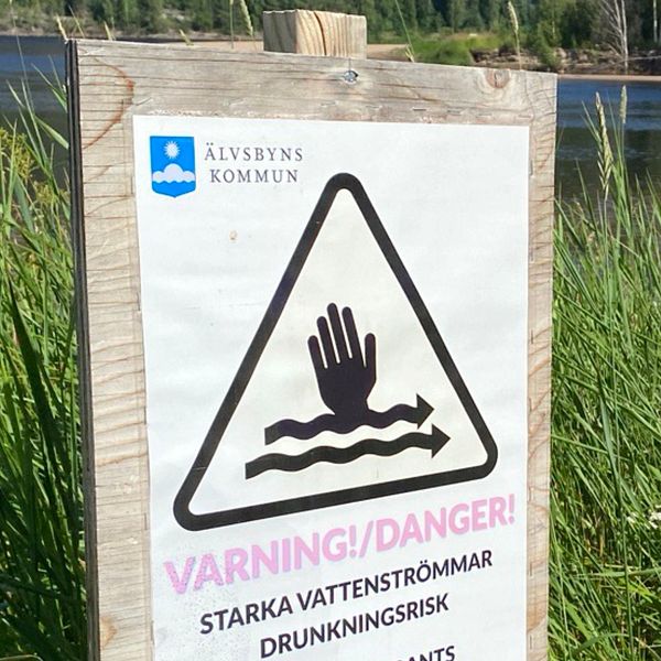 En varningsskylt om starka strömmar vid olycksplatsen i Älvsbyn där en man och ett barn omkom.r